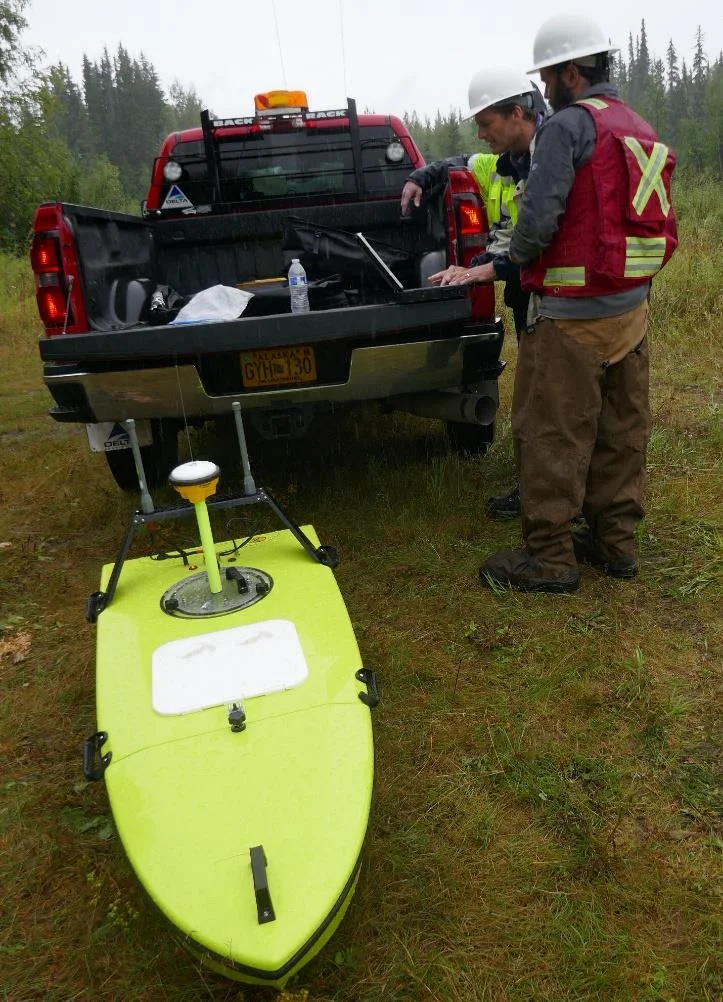 Surveyors beside a pickup truck with the CEE-USV on the ground
