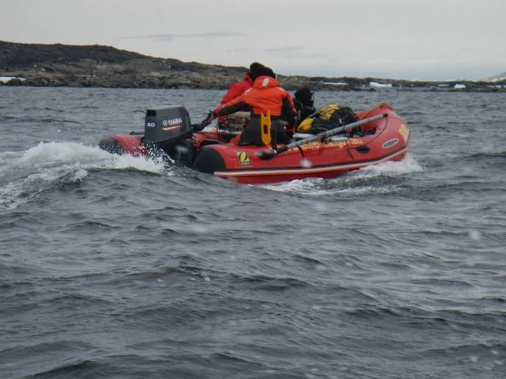 Inflatable survey boat with an outboard motor running through choppy water near the Davis Station shore