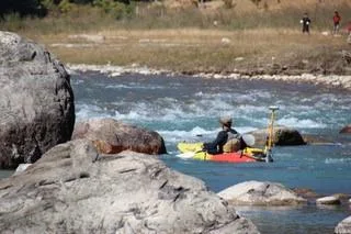 Kayak surveyor beside large rocks on a Bhutan river