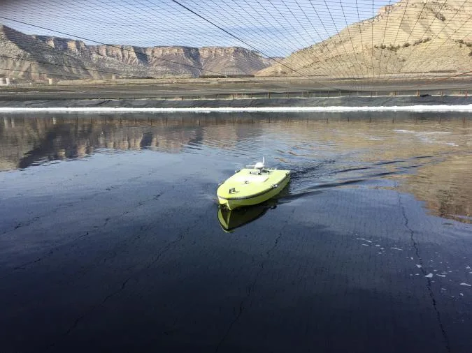 Yellow USV on a lagoon beneath bird netting in a baking soda plant