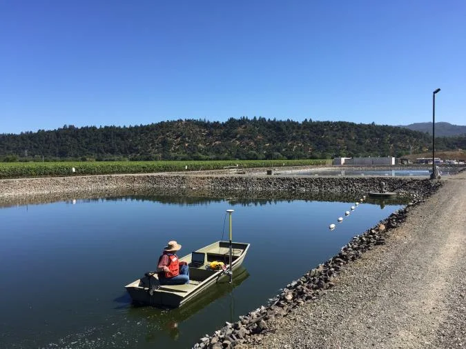 Surveyor in a small boat on an effluent lagoon