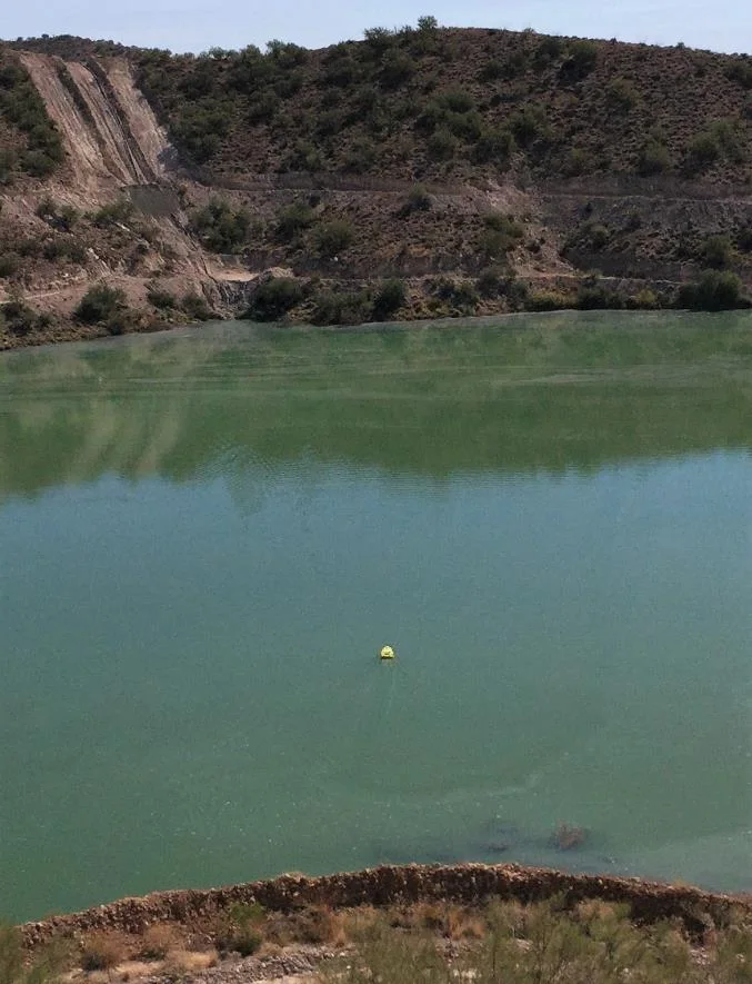 Tailings pond with a small marker buoy on the water