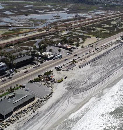 Aerial view of beach nourishment in the foreground and lagoon dredging behind