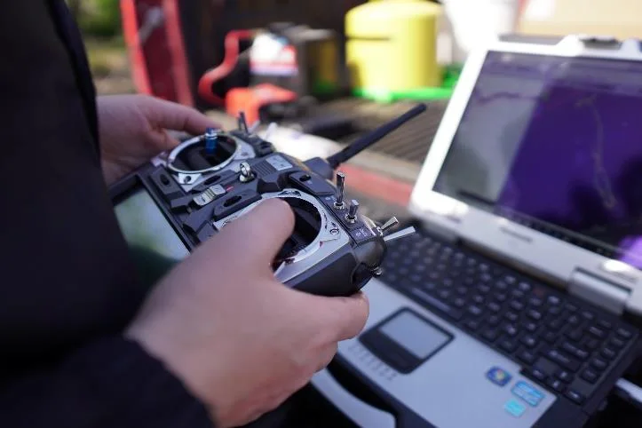 Shore operator steering the CEE-USV with the RC controller next to the field laptop running HYPACK