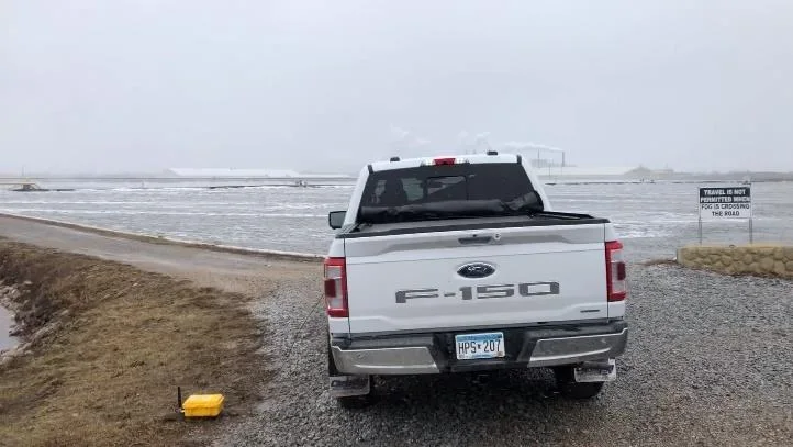 Pickup truck parked at the lagoon edge with the survey equipment outside