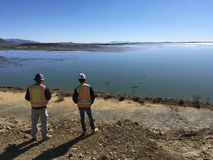 Two operators in hi-vis vests looking over a tailings impoundment