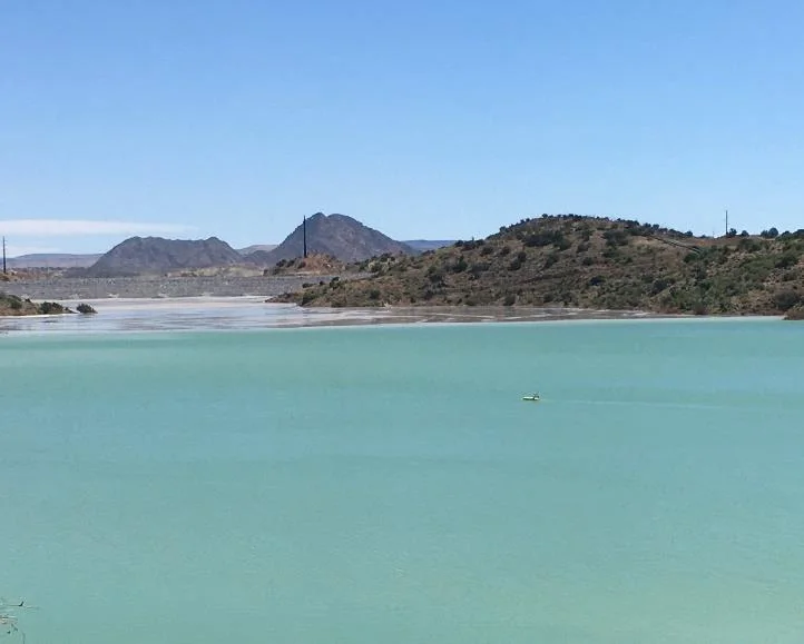 Tailings storage facility with turquoise water and hills behind