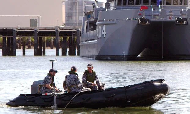 Navy personnel in a RIB with a pole-mounted sensor during commissioning of the Tactical Survey Kits