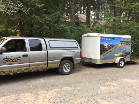 Statewide survey truck and trailer parked among trees