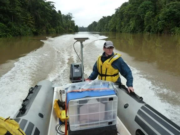 Surveyor in a life jacket aboard an inflatable survey launch on a river in Papua New Guinea